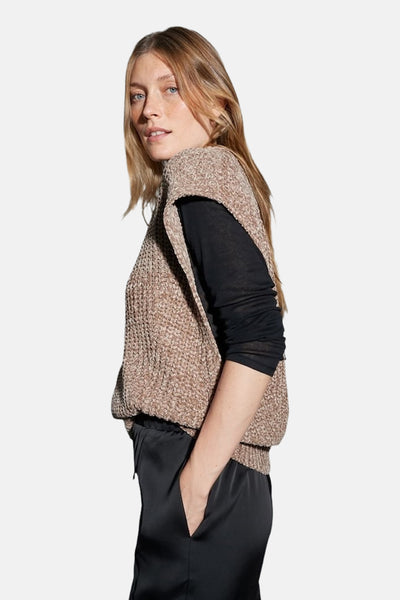 Débardeur taupe de OPUS, porté sur un haut noir à manches longues et un pantalon noir satiné.