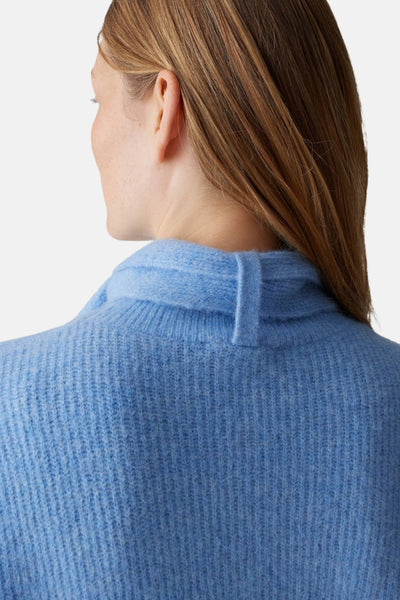 Pull bleu d’OPUS, avec col montant et détail de bride, texture tricotée.