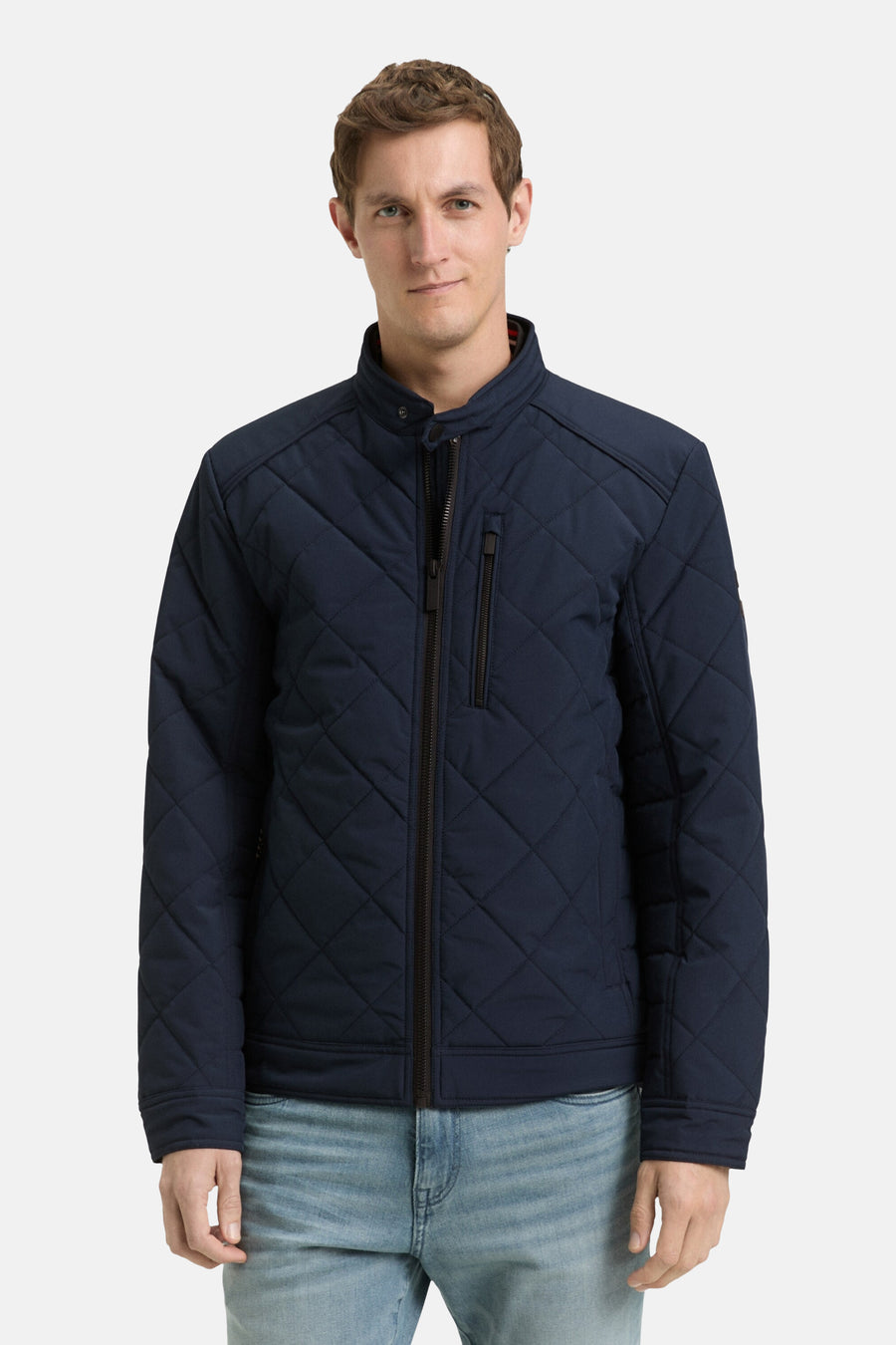 Korte blauwe jas van Tom Tailor met doorgestikt patroon, gedragen over een wit T-shirt en een casual spijkerbroek.