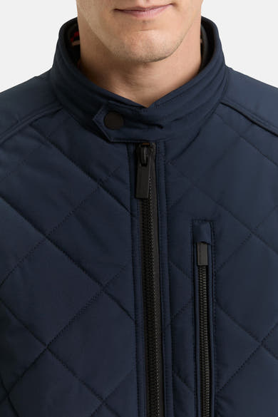 Korte blauwe jas van Tom Tailor, gewatteerd met ritssluiting en opstaande kraag met knoopsluiting.