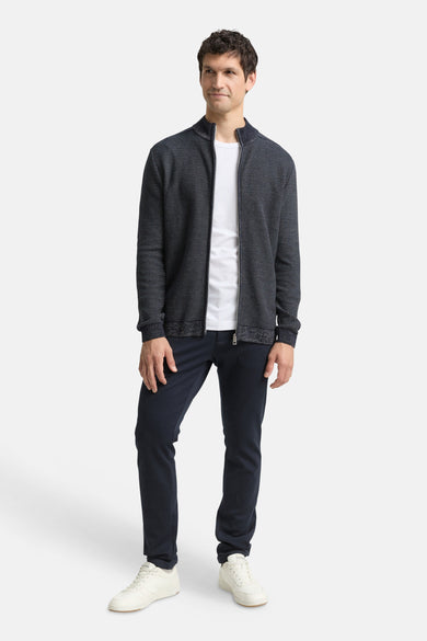 Gilet bleu de Tom Tailor, à motifs texturés, porté avec un t-shirt blanc et un pantalon marine.