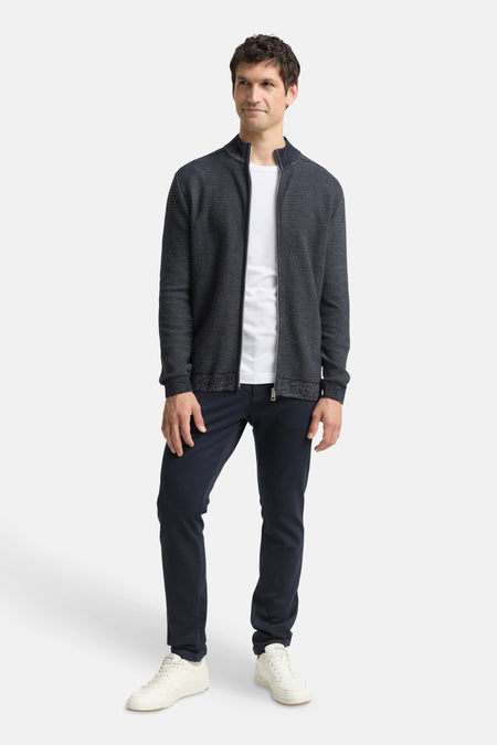 Gilet bleu de Tom Tailor, à motifs texturés, porté avec un t-shirt blanc et un pantalon marine.