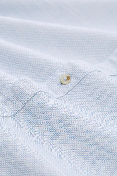 Chemise à manches longues bleue de Tom Tailor avec motif géométrique et texture froissée, détail du bouton.