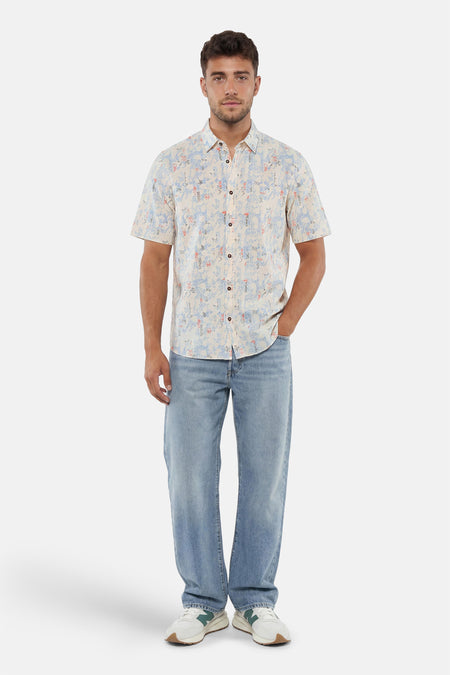 Chemise à manches courtes multicolore de Tom Tailor, à motifs abstraits bleus et rouges, portée avec un jean clair et des baskets.