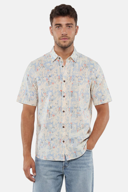 Chemise multicolore à manches courtes de Tom Tailor avec motif abstrait bleu, orange et gris sur fond crème, portée avec un jean clair.