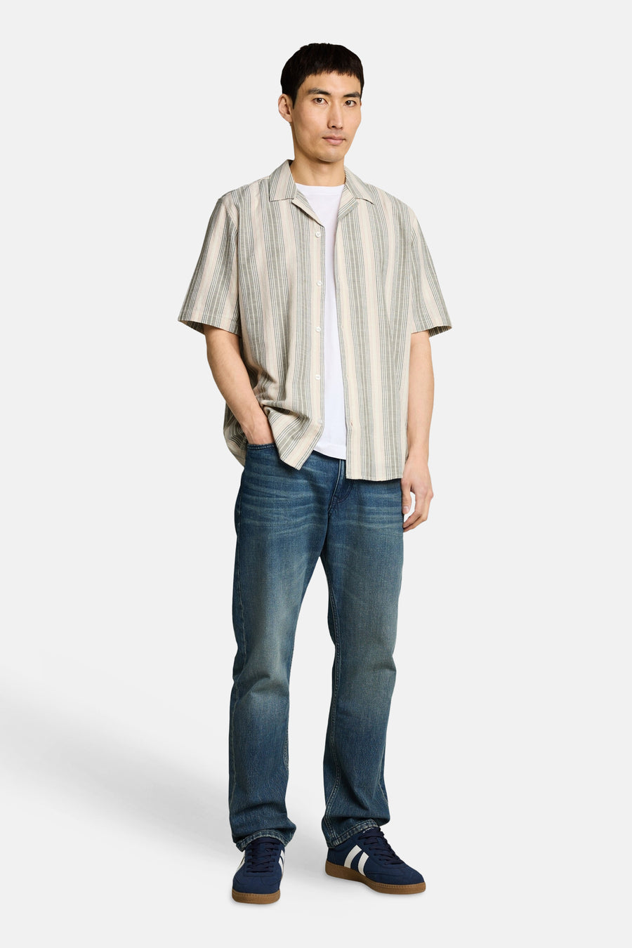 Chemise à manches courtes à rayures multicolores de Tom Tailor, ouverte sur un t-shirt blanc avec un jean et des baskets bleues.
