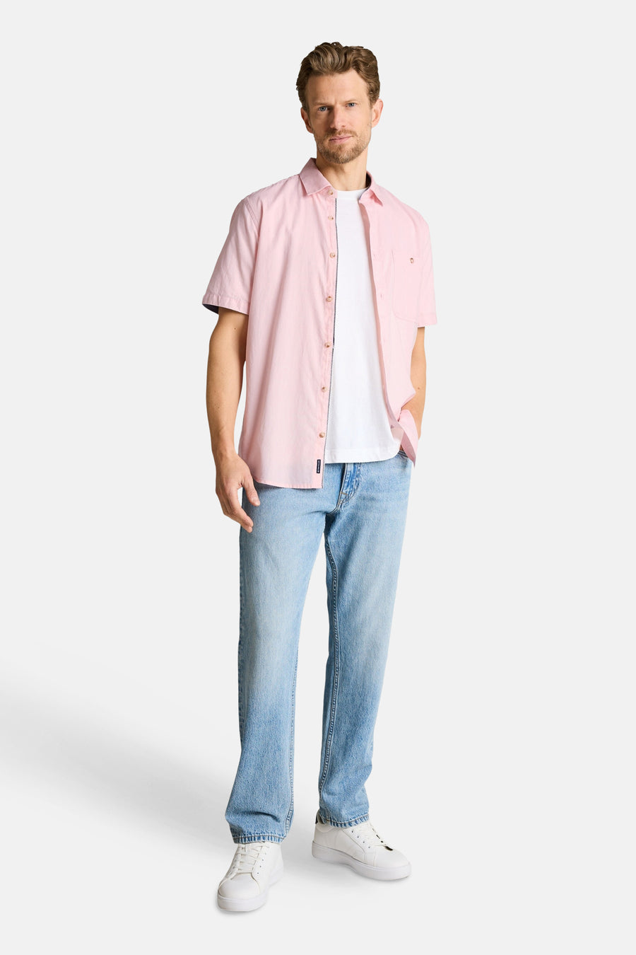 Chemise rose à manches courtes de Tom Tailor ouverte sur un t-shirt blanc, portée avec un jean clair et des baskets.