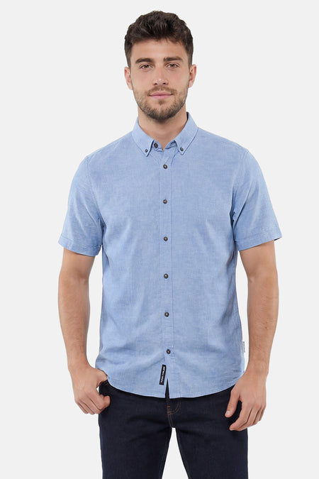 Chemise bleue à manches courtes de Tom Tailor, col boutonné et boutonnée, portée par un homme avec un jean foncé.