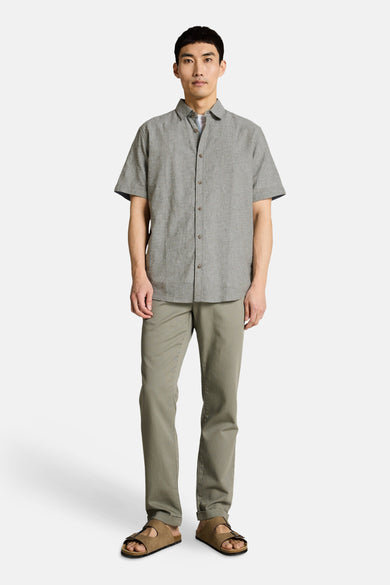 Kaki short-sleeve chemise with button-down front and relaxed fit, worn with olive trousers and brown sandals, full-body front view