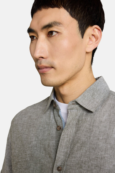 Kaki short-sleeve chemise with textured fabric and button-down front, side view of model wearing white undershirt