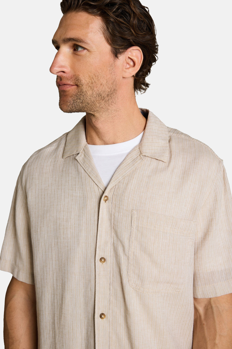 Beige korte mouwen overhemd van Tom Tailor met fijne verticale strepen, cubaanse kraag en borstzak, gedragen open over een wit T-shirt.