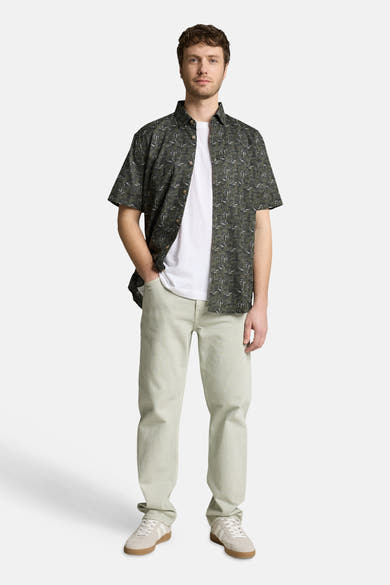 Chemise à manches courtes verte de Tom Tailor avec motifs feuillage, portée ouverte sur un t-shirt blanc.
