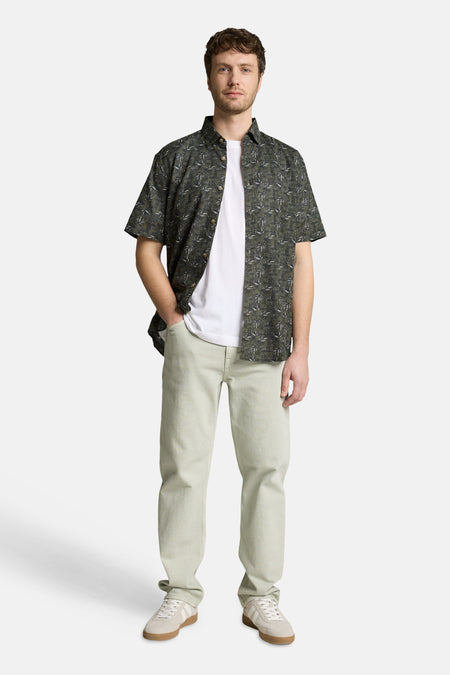Chemise à manches courtes verte de Tom Tailor avec motifs feuillage, portée ouverte sur un t-shirt blanc.