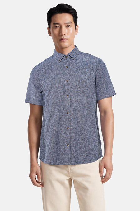 Chemise à manches courtes bleue de Tom Tailor avec col boutonné et motif texturé, portée avec un chino beige.