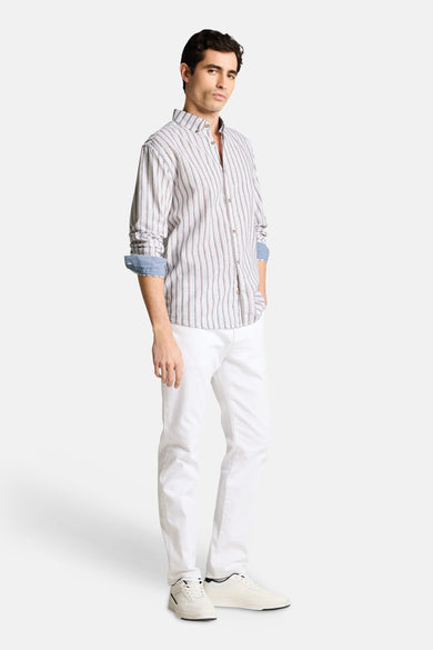 Chemise à rayures multicolores de Tom Tailor avec des manches longues retroussées, portée avec un pantalon blanc et des baskets.