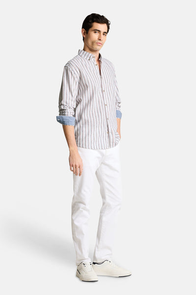 Chemise à rayures multicolores de Tom Tailor avec des manches longues retroussées, portée avec un pantalon blanc et des baskets.