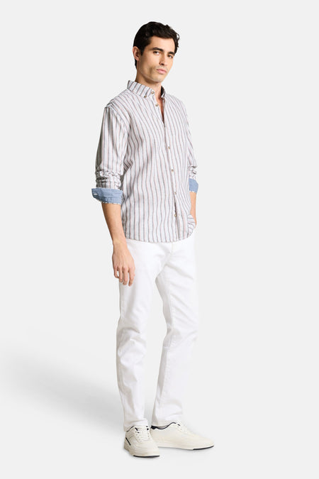Chemise à rayures multicolores de Tom Tailor avec des manches longues retroussées, portée avec un pantalon blanc et des baskets.