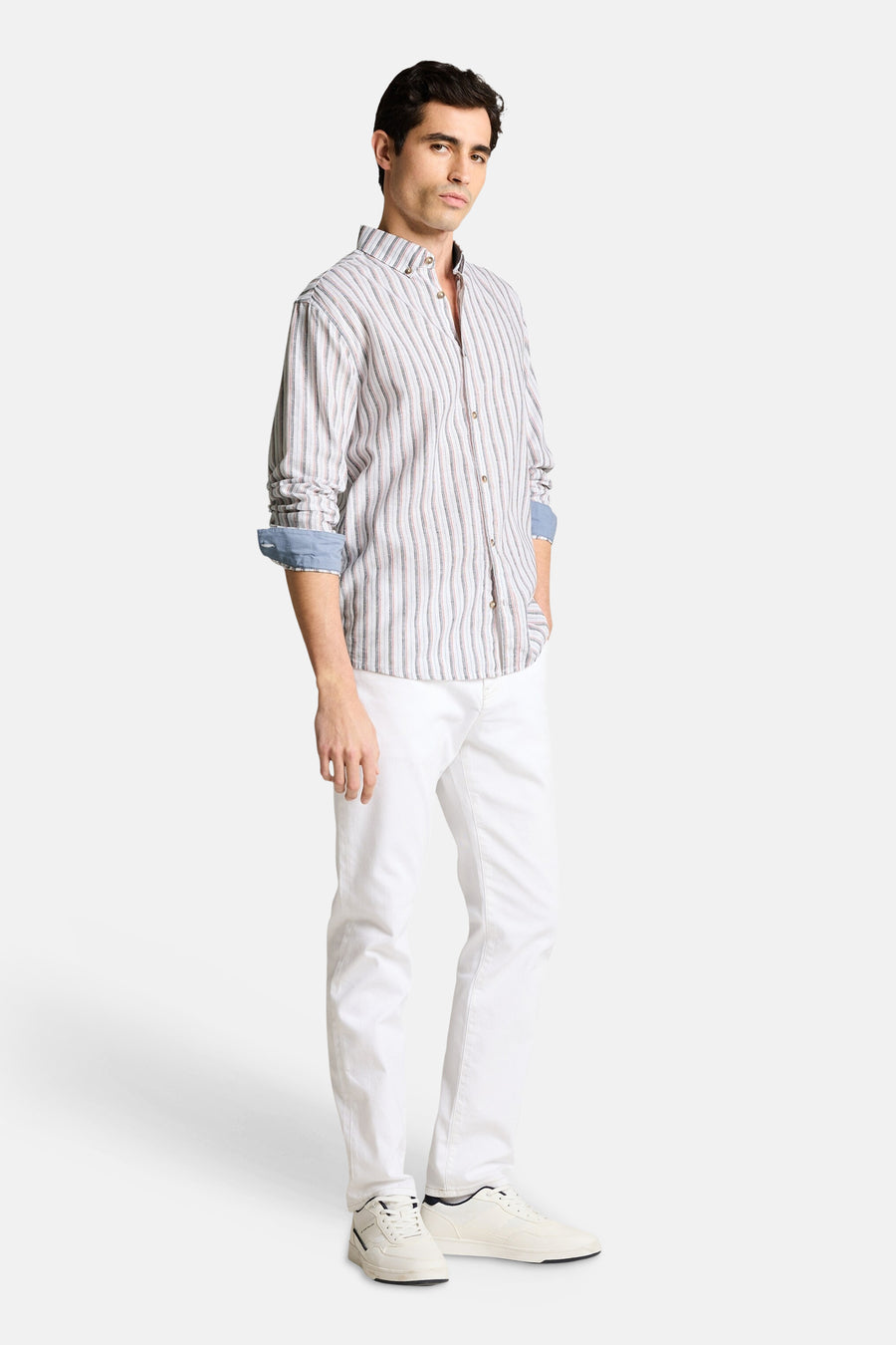 Chemise à rayures multicolores de Tom Tailor avec des manches longues retroussées, portée avec un pantalon blanc et des baskets.