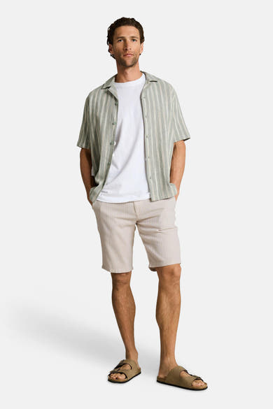 Bermuda beige de Tom Tailor avec rayures verticales, porté avec un t-shirt blanc et des sandales marron.