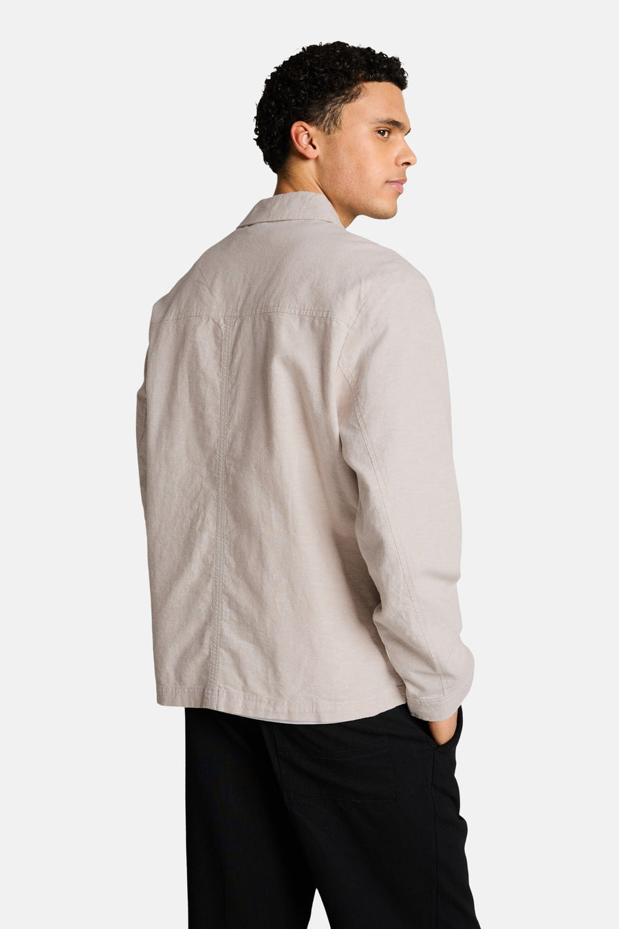 Veste beige Tom Tailor avec manches longues, détail couture au dos, portée avec un pantalon noir.