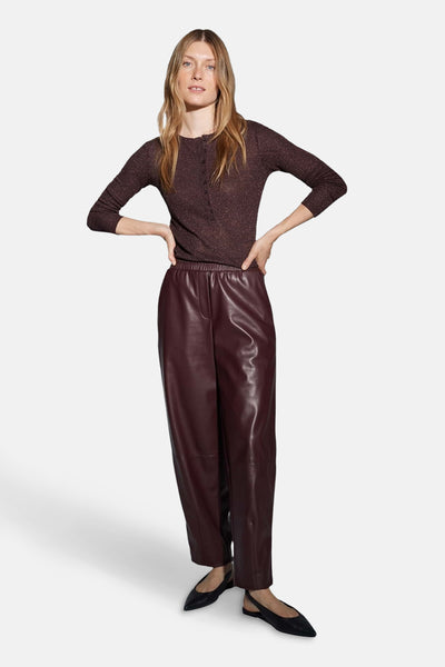 Pantalon bordeaux en similicuir par OPUS, porté avec un haut marron scintillant et des ballerines noires.
