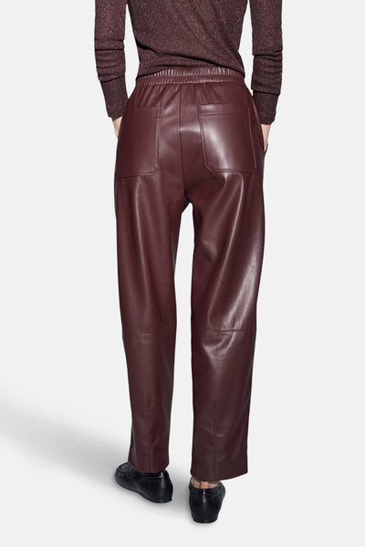 Pantalon bordeaux en cuir, par OPUS, avec poches arrière et taille élastique, vu de dos.
