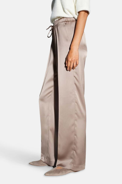 Pantalon taupe en satin by OPUS, coupe ample, porté avec un pull blanc.