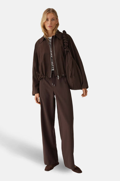 Pantalon de costume brun de OPUS, coupe droite ample avec cordon de serrage, porté avec un t-shirt rayé et une veste marron.