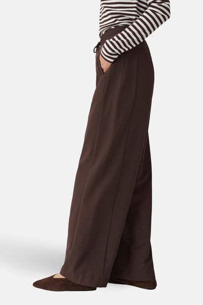 Pantalon de costume brun de OPUS, coupe ample, avec une poche et porté avec un haut rayé.