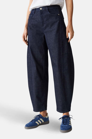 Pantalon ample bleu marine par OPUS, avec poches et coutures apparentes, porté avec des baskets bleues.
