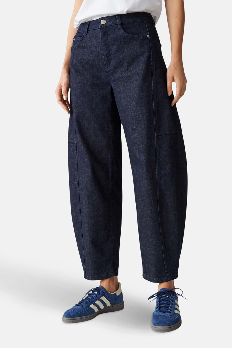 Pantalon ample bleu marine par OPUS, avec poches et coutures apparentes, porté avec des baskets bleues.
