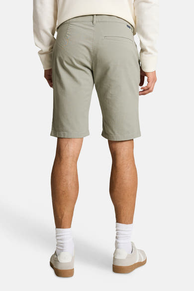 Short vert de Tom Tailor, vu de dos, avec poche passepoilée, porté avec un haut gaufré et des baskets claires.
