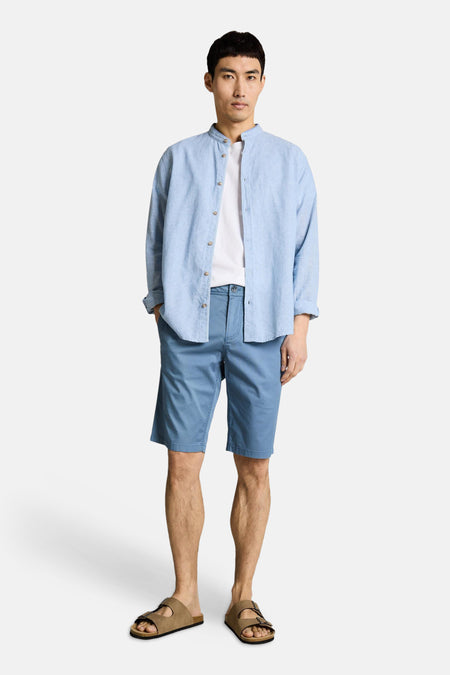 Bermuda bleu de Tom Tailor, porté avec une chemise bleue en lin et un t-shirt blanc.