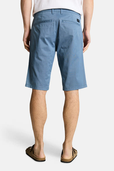Bermuda bleu de Tom Tailor, avec poches arrière et texture subtile, porté avec des sandales marron.