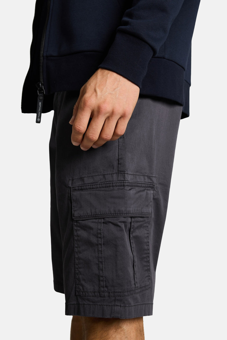 Short cargo gris foncé par Tom Tailor, détail de poche cargo, porté avec un sweat-shirt bleu marine, vue de côté recadrée.