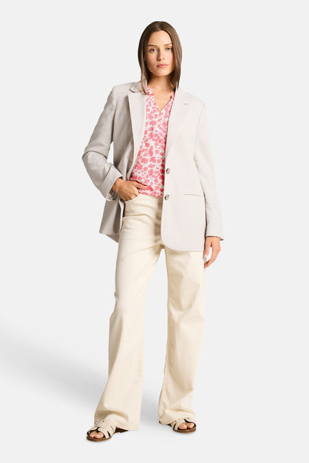 Chemisier à manches courtes multicolore de Tom Tailor, à motifs floraux roses, porté sous un blazer gris clair avec un pantalon beige.