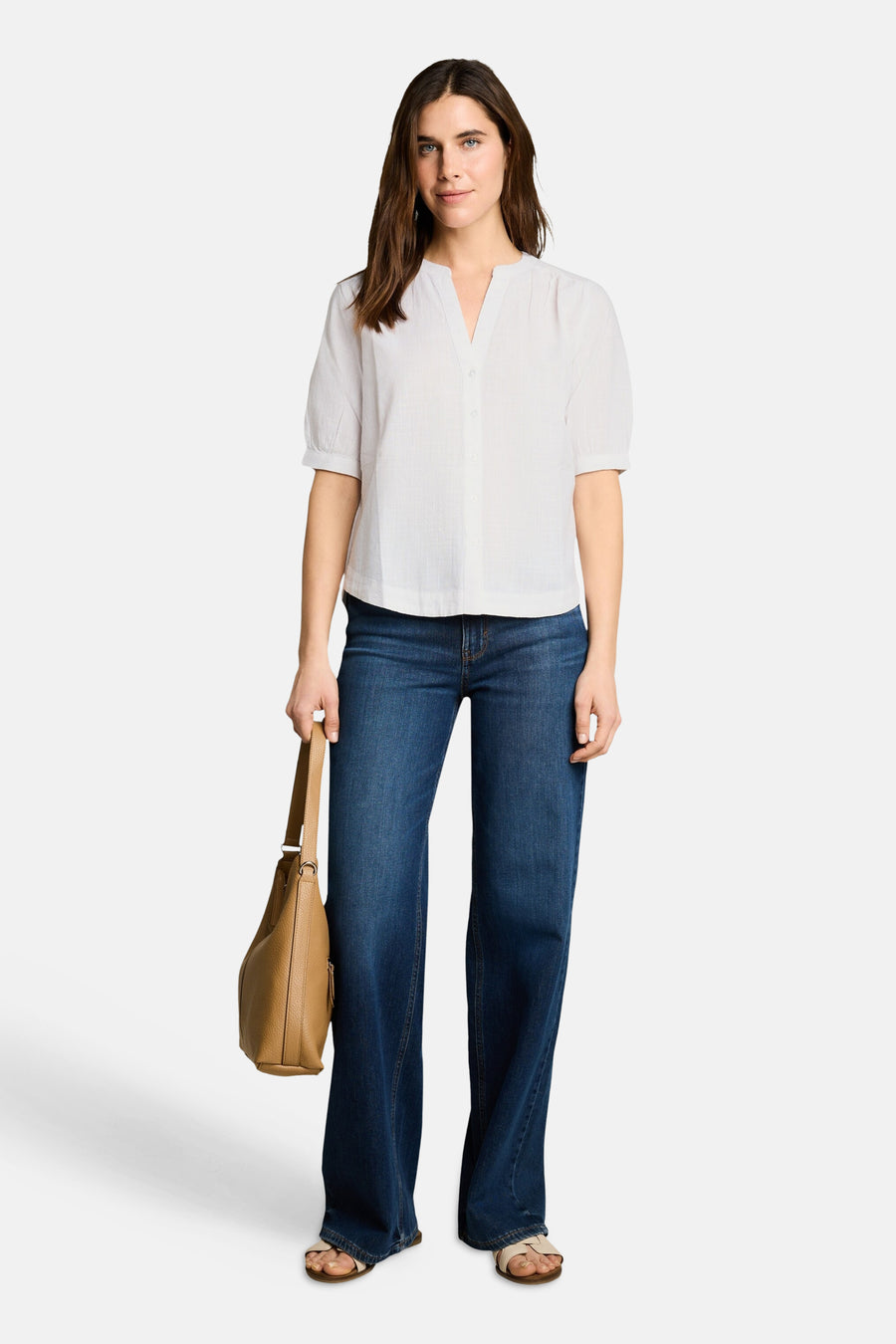 Chemisier blanc à manches courtes de Tom Tailor, col V, boutonné, porté avec un jean large et un sac beige.
