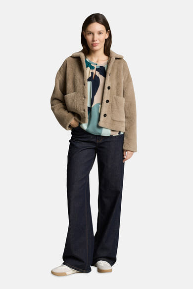 Chemisier multicolore à manches courtes par Tom Tailor, avec motifs abstraits, porté avec une veste en peau lainée et un jean évasé.