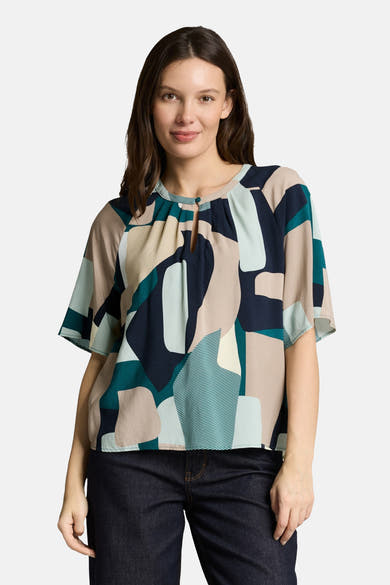 Chemisier multicolore à manches courtes par Tom Tailor, imprimé avec un motif géométrique abstrait et porté avec un jean foncé.