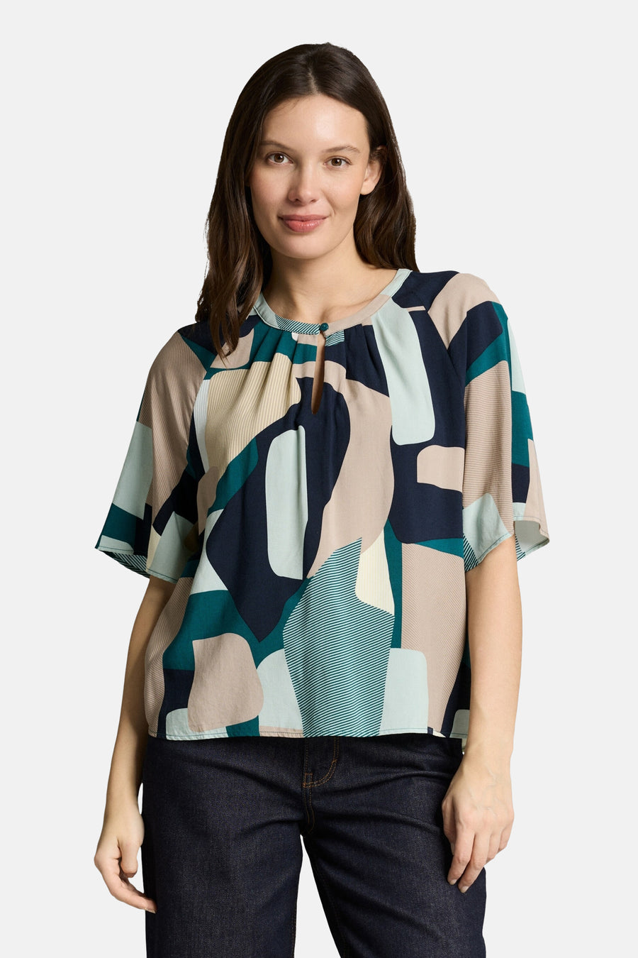 Chemisier multicolore à manches courtes par Tom Tailor, imprimé avec un motif géométrique abstrait et porté avec un jean foncé.