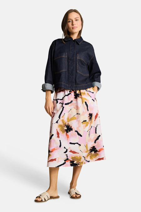 Jupe 3/4 multicolore de Tom Tailor avec motif abstrait rose, or et noir, portée avec un blouson en jean foncé.