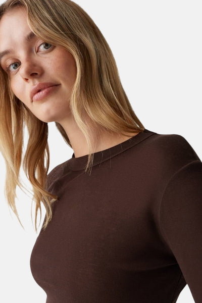 T-shirt à manches longues brun d'OPUS, en jersey côtelé, porté par un modèle avec des cheveux blonds ondulés.