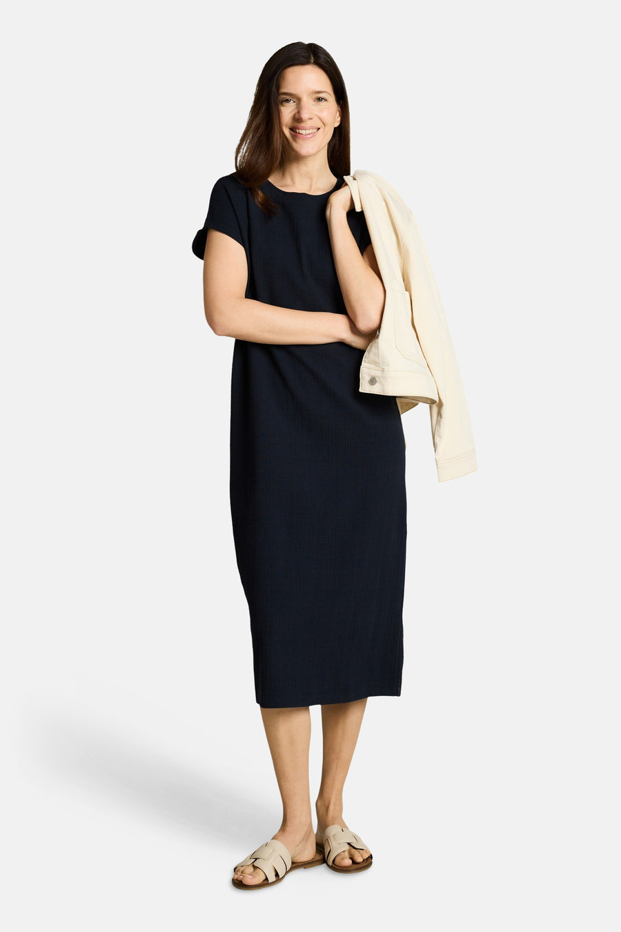 Robe midi côtelée bleu marine de Tom Tailor, portée par une femme avec une veste claire et des sandales beiges.
