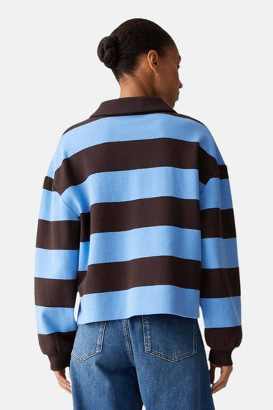 Pull à col en V multicolore de OPUS, à rayures marron et bleu ciel, porté avec un jean.
