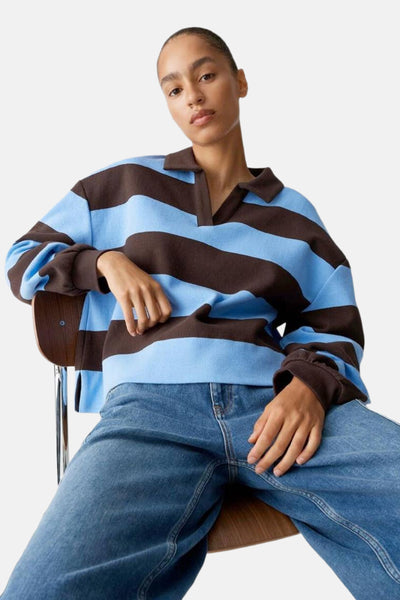 Pull à col en V rayé bleu et marron par OPUS, porté avec un jean bleu ample.
