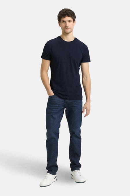 T-shirt à manches courtes bleu de Tom Tailor, porté avec un jean bleu foncé et des baskets blanches.