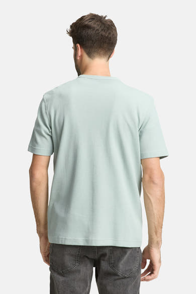 T-shirt à manches courtes vert par Tom Tailor, avec une texture gaufrée, porté avec un jean gris, vue de dos.