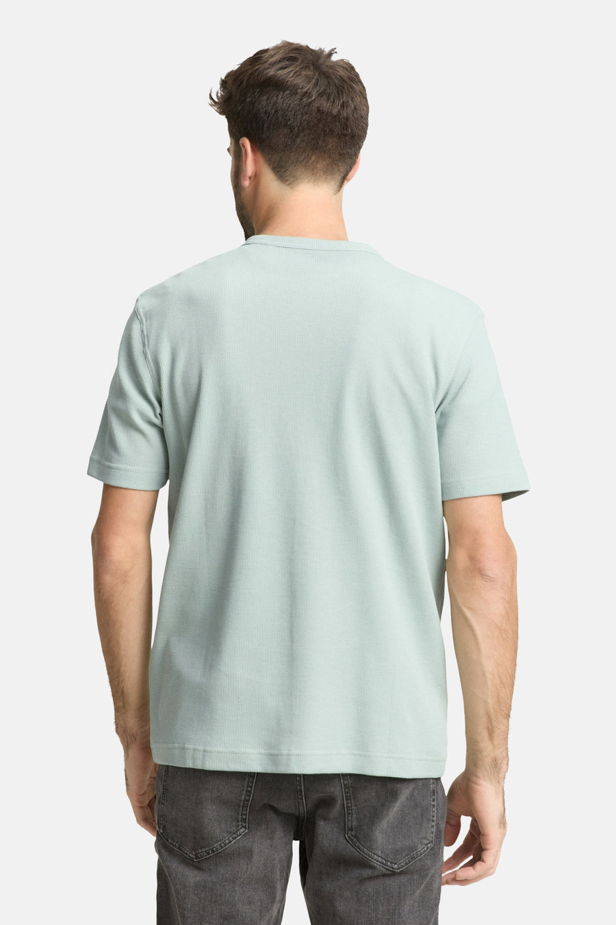 T-shirt à manches courtes vert par Tom Tailor, avec une texture gaufrée, porté avec un jean gris, vue de dos.