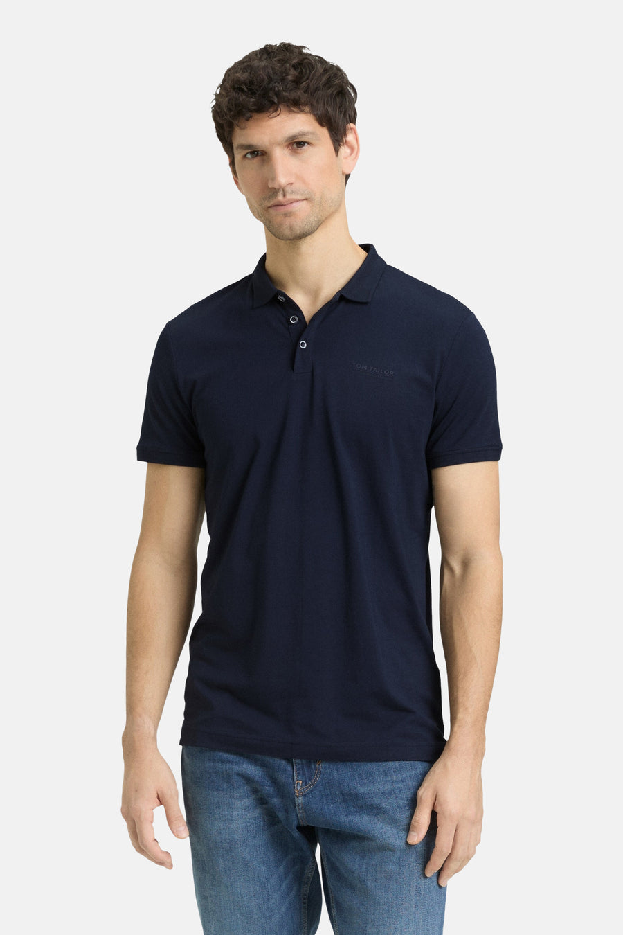 Blauw poloshirt met korte mouwen van Tom Tailor, gedragen met een spijkerbroek en witte sneakers.
