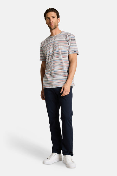 T-shirt à rayures multicolores de Tom Tailor, porté avec un pantalon bleu marine et des baskets blanches.